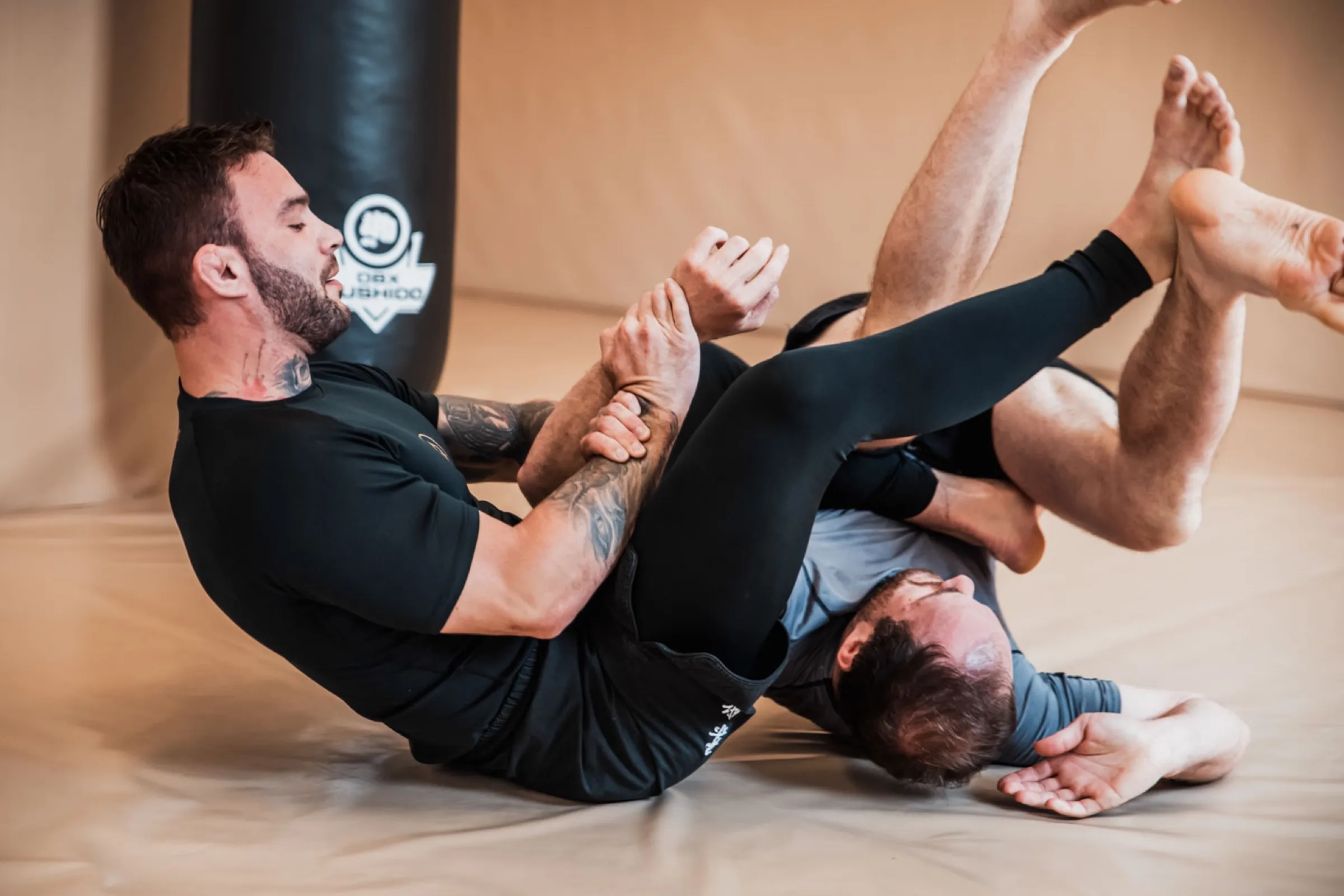 Grappling bez kimona: Martin nasazuje partnerovi páku na loket, oba leží na tatami.